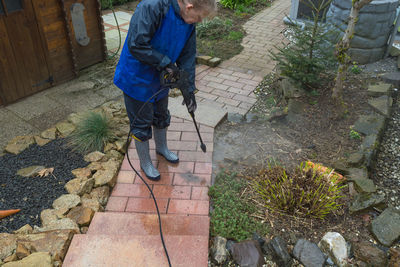 High angle view of woman cleaning footpath