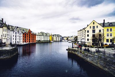 Buildings by river against sky in city