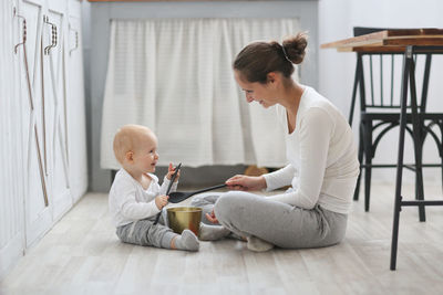 Mom and baby playing together on the kitchen floor, living style in a real scandinavian