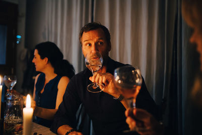 Man drinking wine while sitting with female friends at dinner party