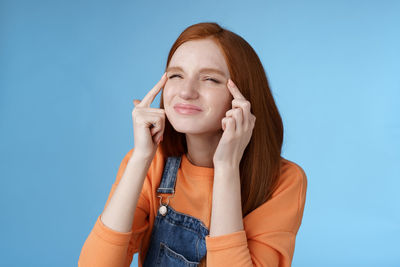 Portrait of a smiling young woman against blue background