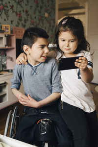 Sister showing video to autistic brother on mobile phone at home