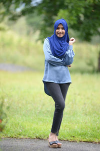 Full length portrait of young woman standing on field