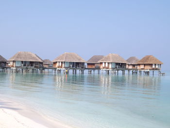 Stilt houses by sea against clear sky