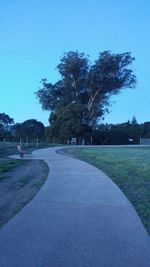 Road amidst trees against clear sky