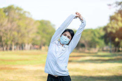 Woman wearing mask exercising at park