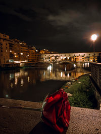 Illuminated city by river against sky at night