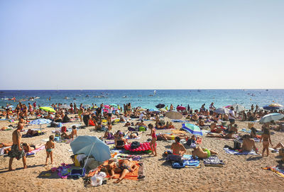 People at beach against clear sky