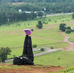 Full length of young woman lying with feet up on field