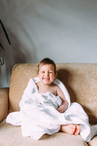Cheerful smiling girl sitting on sofa at home