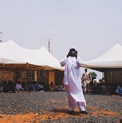 Man photographing woman against clear sky