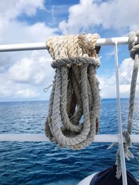 Close-up of rope tied on boat sailing in sea against sky