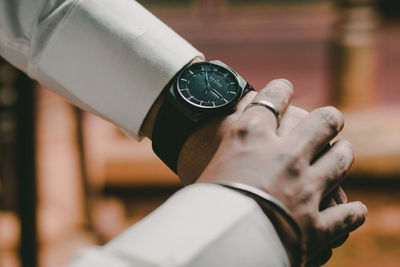 Close-up of hand holding clock against blurred background