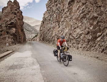 A cyclist rides through a rock cut on a mountain road in morocco