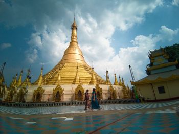 People walking in temple building against sky