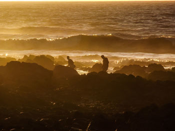 Silhouette man on mountain against sky during sunset