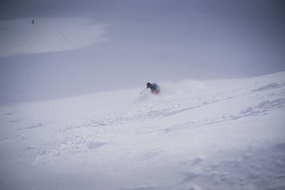 Man skiing on snowcapped mountain against sky