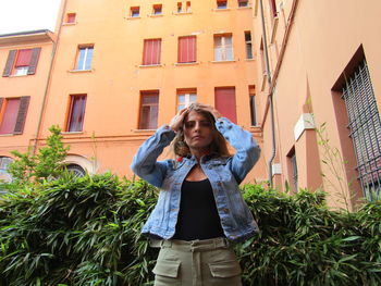 Portrait of young woman standing against building