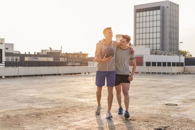 Friends playing basketball at sunset on a rooftop