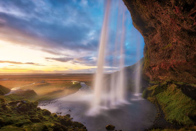 Scenic view of waterfall against sky during sunset