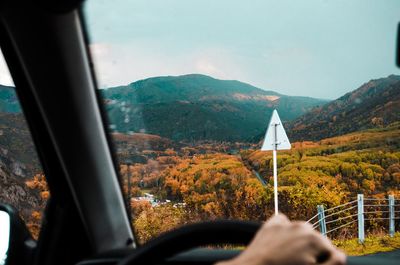 Cropped image of person driving car against mountains