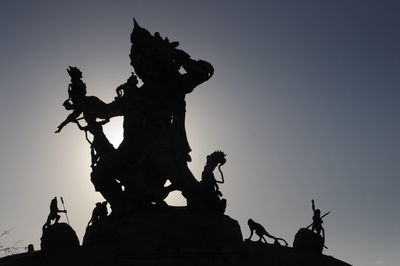 Low angle view of silhouette statue against sky