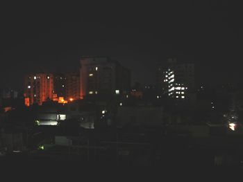 Illuminated buildings in city against sky at night