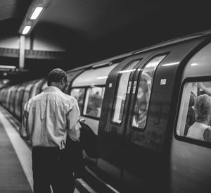 Rear view of man standing by train at subway station