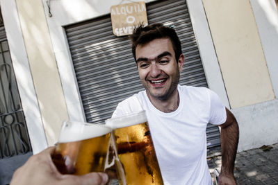 Happy man toasting beer glass while sitting in yard