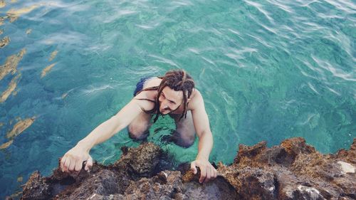 Man climbing on rocks from the sea