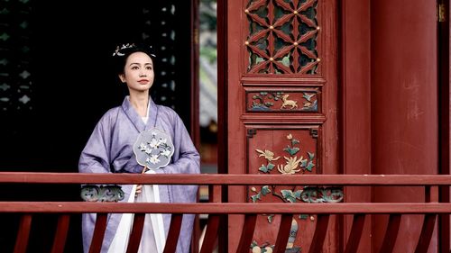 Portrait of young woman standing against wall