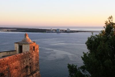 Scenic view of sea by building against sky during sunset