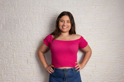 Portrait of a smiling young woman against wall