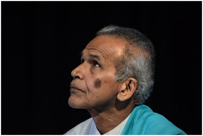 Side view of man looking away against black background