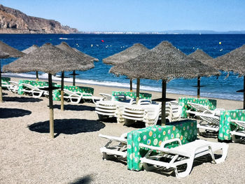 Deck chairs on beach against sky