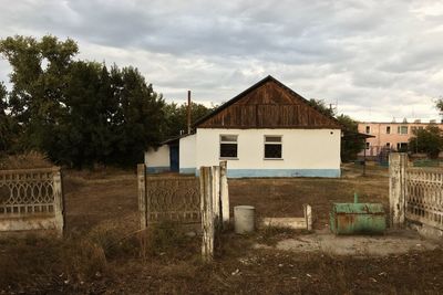 House on field by building against sky