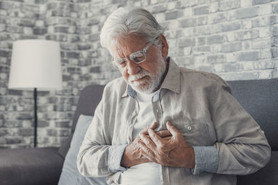 Young man looking away while sitting on sofa at home