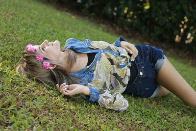 Smiling young woman wearing flowers while lying on field