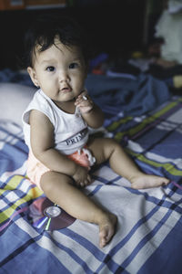 High angle view of cute baby sitting on bed at home