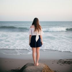 Rear view of woman standing at beach