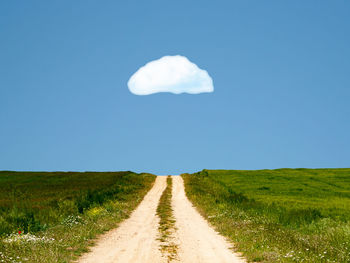 Road amidst field against sky