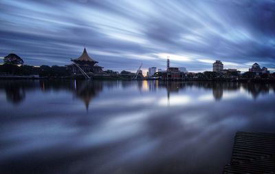 View of city at waterfront against cloudy sky