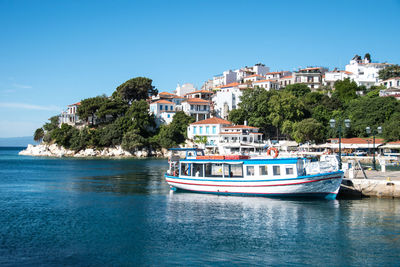 Boats in sea by town against clear blue sky