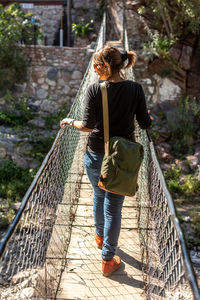 Rear view of woman walking on footbridge