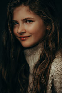 Close-up portrait of cute smiling girl against black background