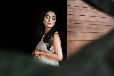 Woman standing by wooden wall