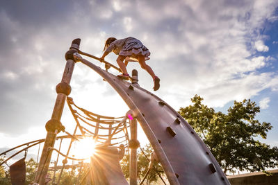 Low angle view of boy playing on playground against sky