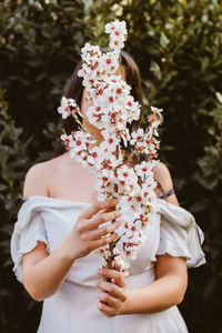 Midsection of woman holding flowering plant