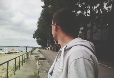 Rear view of man standing by tree against sky