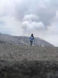 Rear view of man standing on mountain against sky